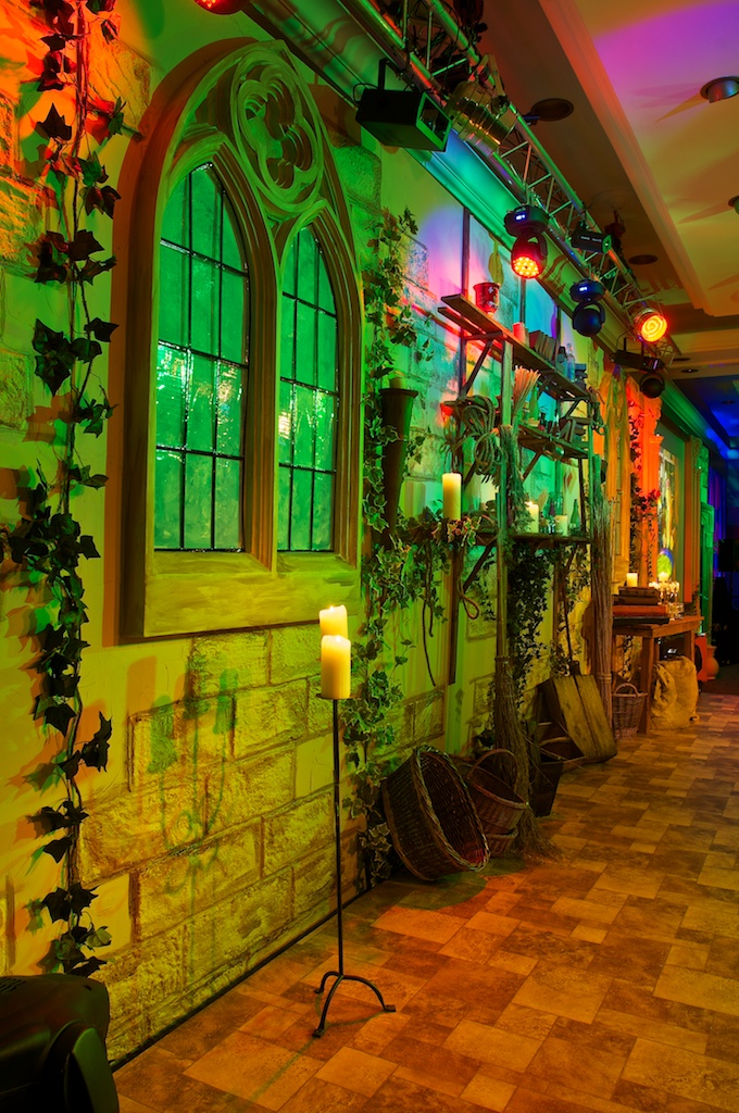 An example of conference stage design featuring a large cathedral-like window, coloured spotlights above, with training ivy and candles.