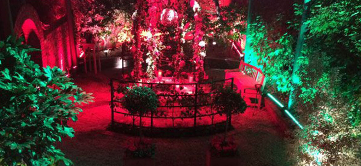 Beautiful outdoor venue in Knightsbridge for corporate anniversary event at night with red and green lights as example of corporate event production.