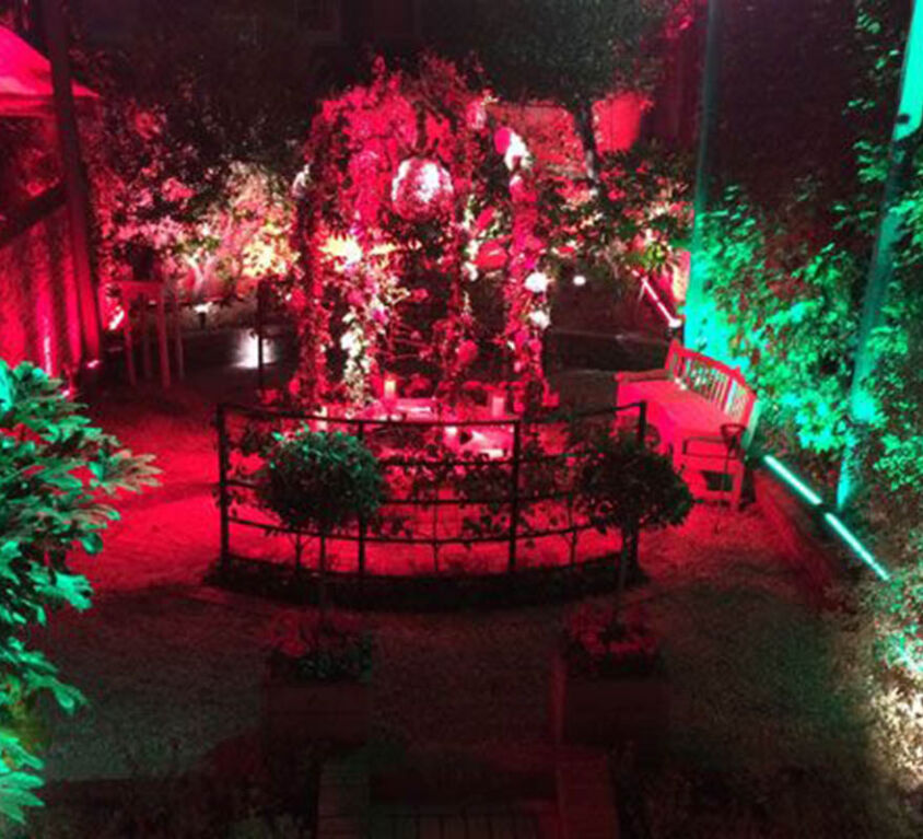 Beautiful outdoor venue in Knightsbridge for corporate anniversary event at night with red and green lights as example of corporate event production.