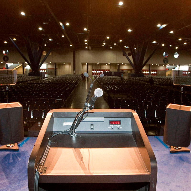 Empty conference hall showing chairs and lectern in foreground with microphone illustrating conference equipment hire or AV hire.