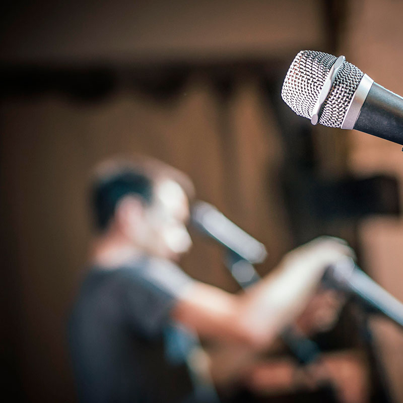 Blurred image of conference stage design being set up by a man straightening microphones, working for an event production company.